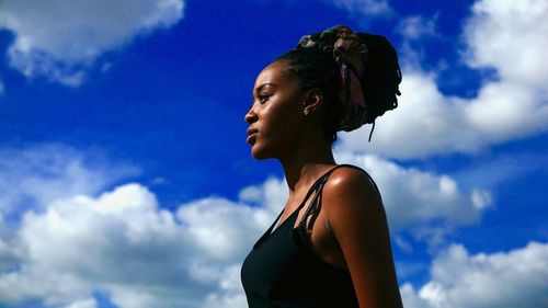 Low angle portrait of woman standing against sky