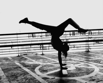 Full length side view of teenager doing handstand by railing