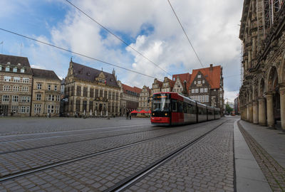 Cars on street by buildings against sky in city