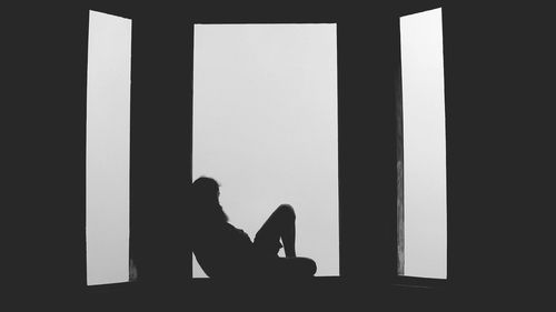 Silhouette of man sitting on floor