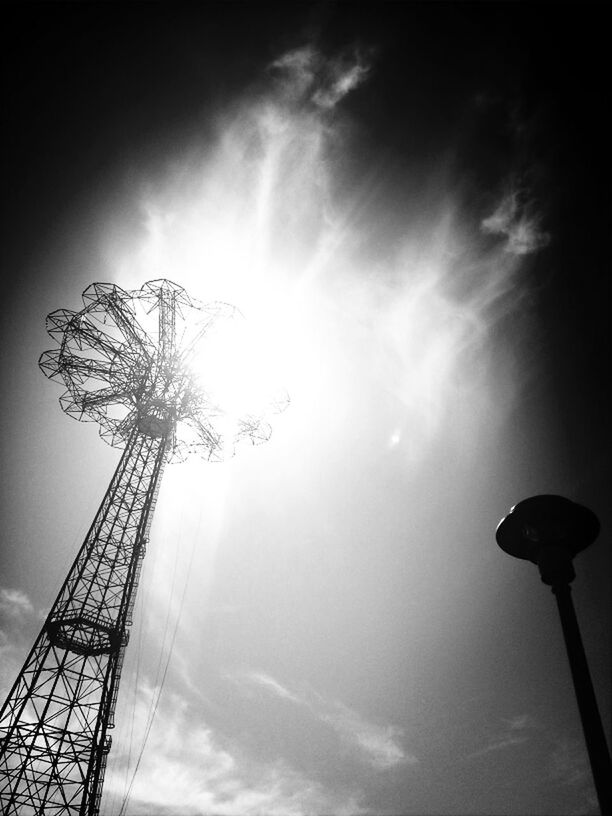 low angle view, sky, tall - high, silhouette, tower, built structure, tree, communications tower, cloud - sky, sun, architecture, outdoors, no people, street light, lighting equipment, nature, tall, dusk, day, sunbeam