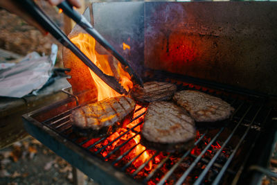 Cropped image of man preparing food on barbecue grill in yard