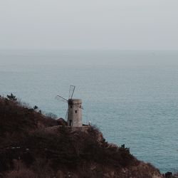 Lighthouse by sea against sky