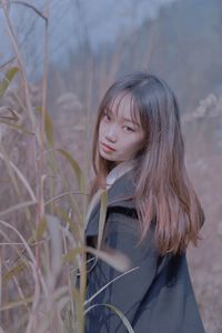 Young woman standing against plants