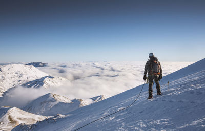 Rear view of man skiing on snowcapped mountain against sky