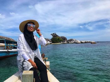 Young woman in hat by sea against sky