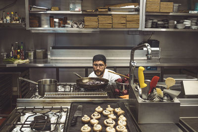 Male chef cooking mushrooms in commercial kitchen