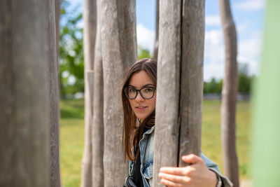 Portrait of woman smiling by tree trunk