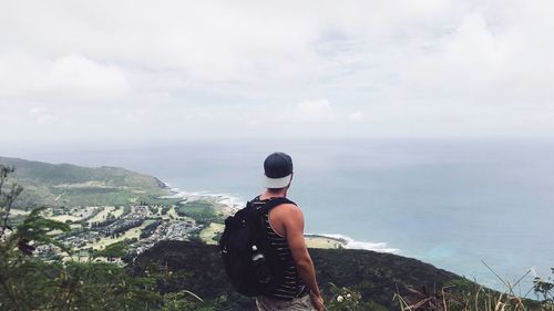 Rear view of man looking at sea against sky