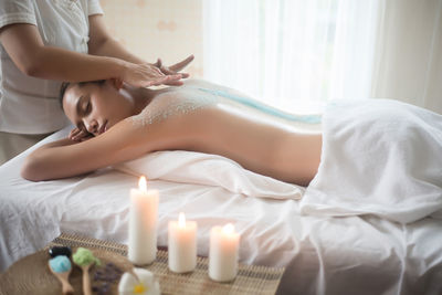 Midsection of therapist massaging young woman in spa