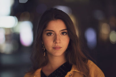 Close-up portrait of young woman while standing outdoors at night