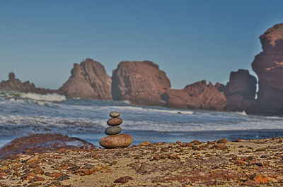 Stack of rocks on beach against clear sky