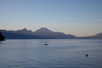 Scenic view of sea and mountains against clear sky