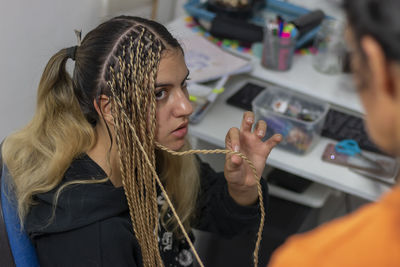 A stylist mother getting her teenage daughter senegalese braids in her home. 