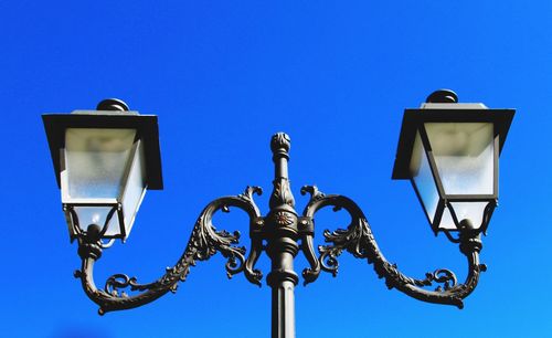 Low angle view of street light against blue sky