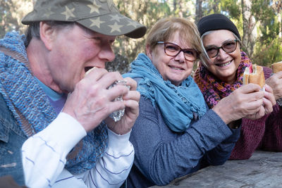 Portrait of smiling senior women having food with friend in forest