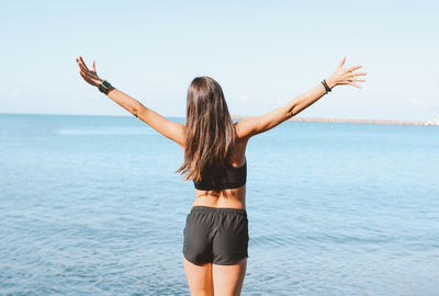 Rear view of woman standing in sea against sky