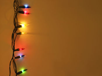Close-up of illuminated string light over yellow background