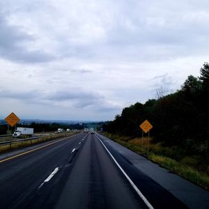 Road by trees against sky