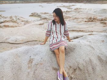 Full length of young woman relaxing at sandy beach