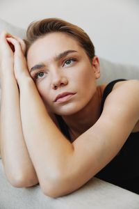 Portrait of young woman looking away against wall