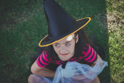 High angle view of girl wearing witch hat sitting on field