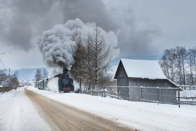 Winter landscape with a steam train rolling next to a road