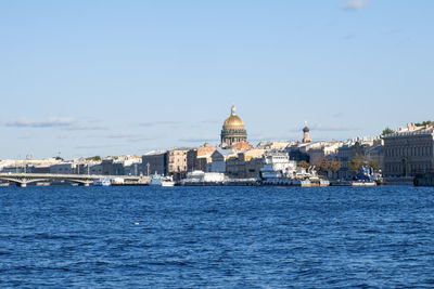 Buildings by sea against clear sky