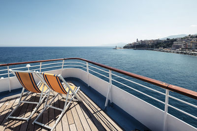 France, haute-corse, deck chairs on bow of ferry sailing toward coast of corsica island