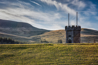 Historic building on field by mountains against sky