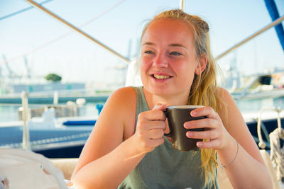 Close-up portrait of a smiling young woman drinking water