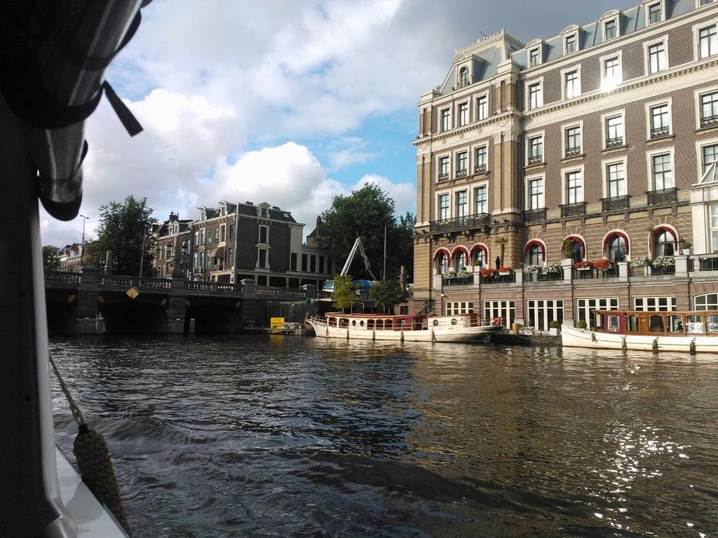 architecture, building exterior, built structure, water, sky, waterfront, city, cloud - sky, reflection, building, transportation, window, cloud, incidental people, canal, nautical vessel, mode of transport, day, river, city life