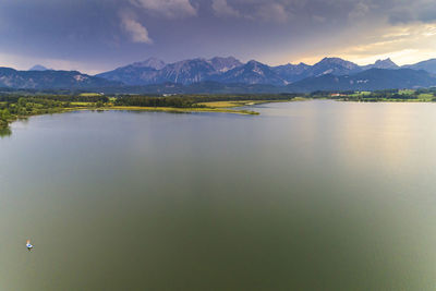 Scenic view of calm lake by mountains against sky during sunset