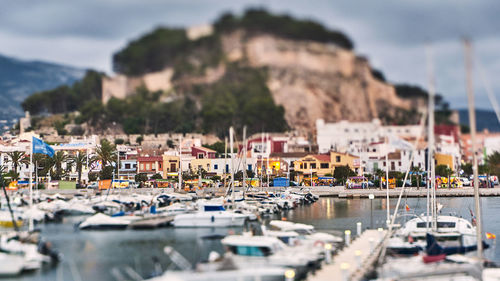 Sailboats moored in harbor by buildings in city