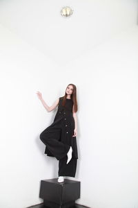 Young woman standing against white wall