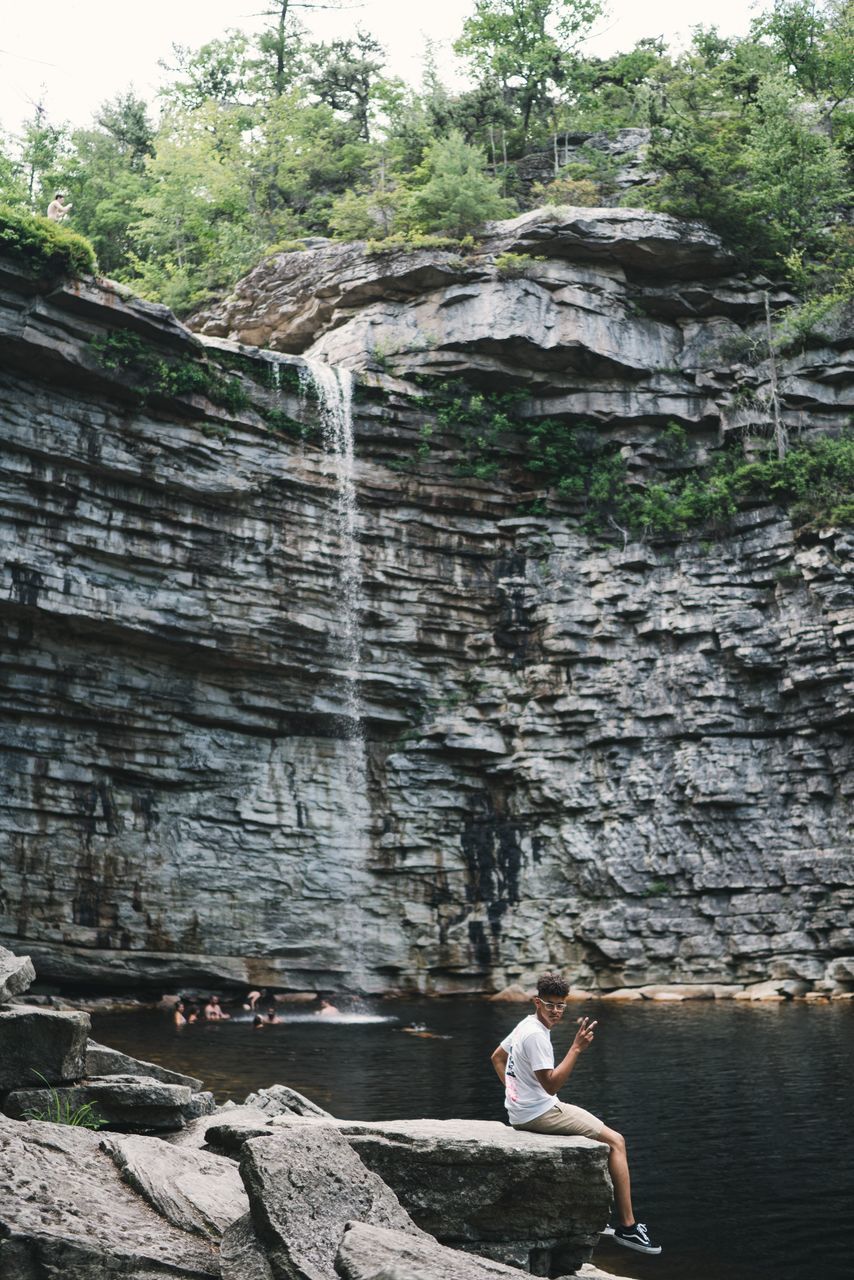 real people, leisure activity, one person, lifestyles, solid, water, women, rock, rock - object, day, architecture, nature, young adult, adult, full length, rock formation, young women, casual clothing, outdoors