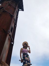 Low angle view of woman standing by built structure against sky