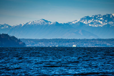 Scenic view of sea and mountains against blue sky