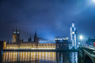 River by illuminated buildings against sky at night