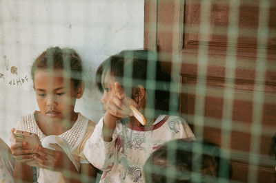 Portrait of young woman looking through window