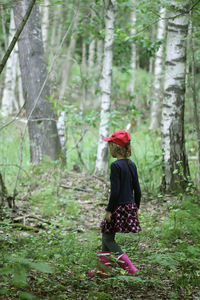 Rear view of woman standing on field in forest