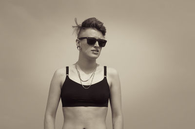 Young woman wearing sunglasses while standing against sky