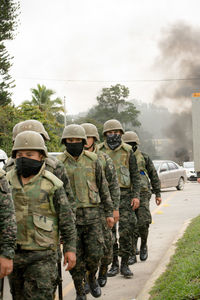 Soldiers wearing uniform walking on road in city