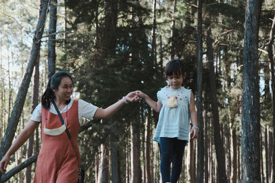 Smiling mother and daughter walking in forest