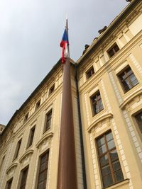 Low angle view of flag on building in city against sky