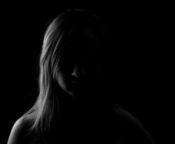 Close-up portrait of a young woman in darkroom