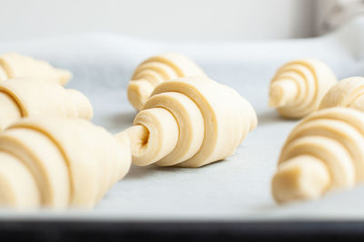 Semifinished or unbaked croissant on a baking sheet. puff pastry baking. close up.