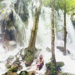 Woman sitting on rock in forest