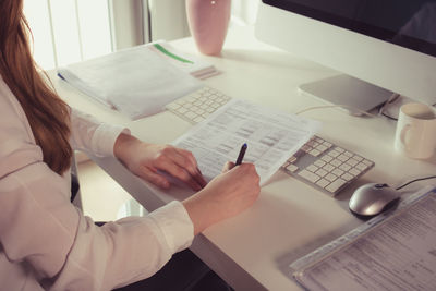 Midsection of woman using laptop on table