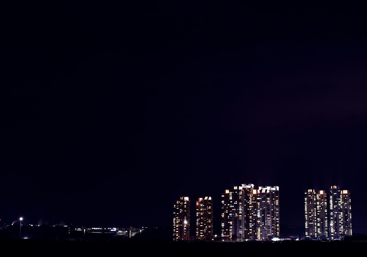 night, illuminated, architecture, built structure, building exterior, city, copy space, clear sky, dark, cityscape, skyscraper, modern, low angle view, sky, no people, outdoors, city life, development, travel destinations, urban skyline